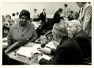a woman speaking with two men at a courtroom bench