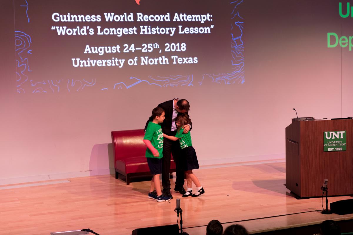 man hugging two children on a stage