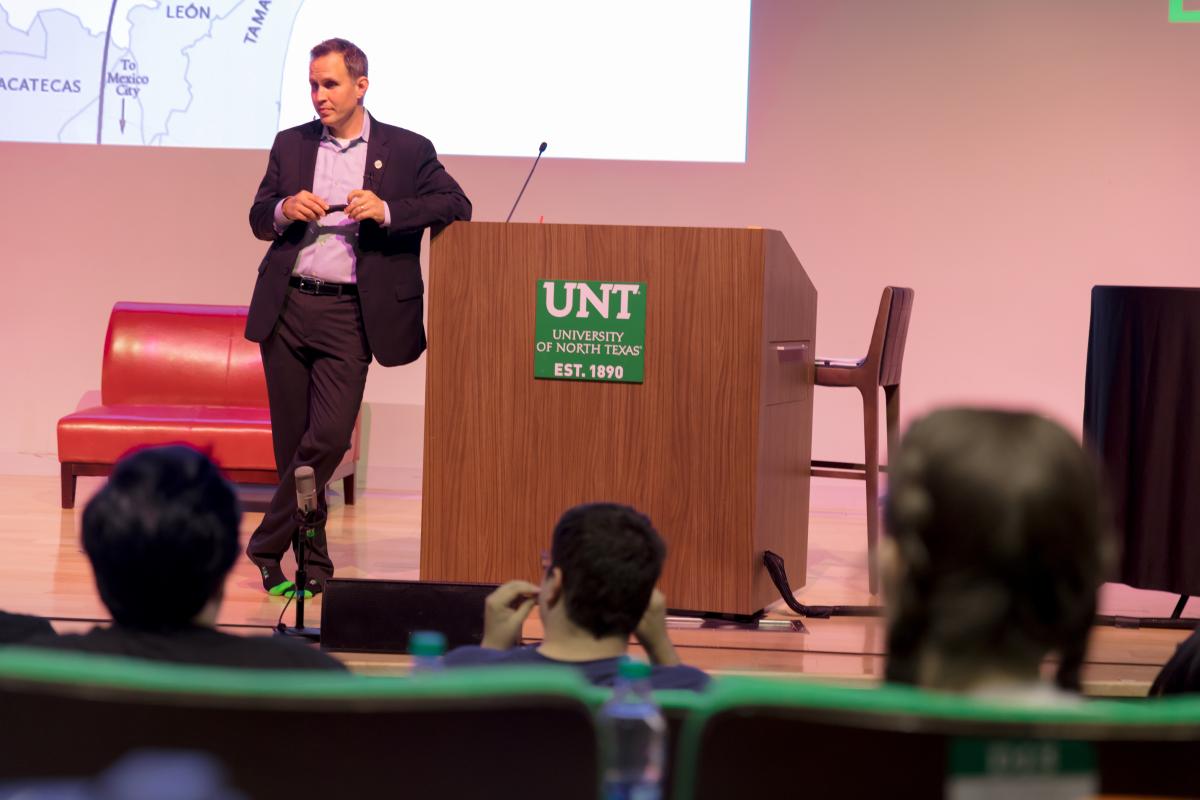 man on a stage leaning on a podium