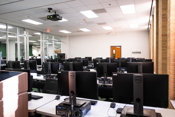 computer classroom with computer stations and presentation screen as seen from front-left