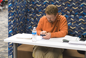 person with open books and phone in an individual study station